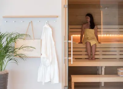 a woman in a yellow dress sitting in a sauna at Hotel Torgglhof in Caldaro