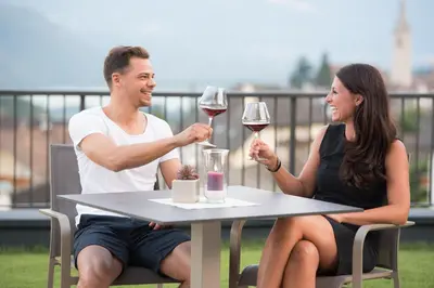 a man and woman sitting at a table with wine glasses at Hotel Torgglhof in Caldaro
