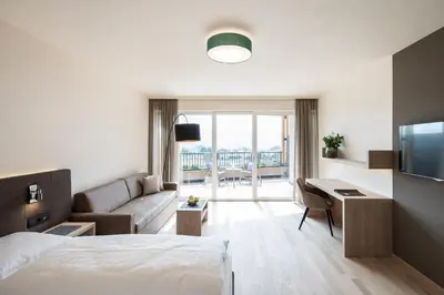 a hotel room with a bed and a couch and a desk at Hotel Torgglhof in Caldaro