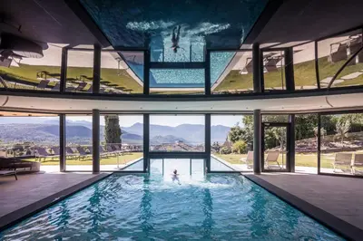 a person in a swimming pool in a house with windows at Hotel Torgglhof in Caldaro