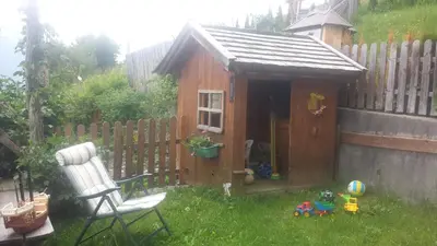 a small wooden shed with a chair in a yard at Pension Schönblick in Campo di Trens
