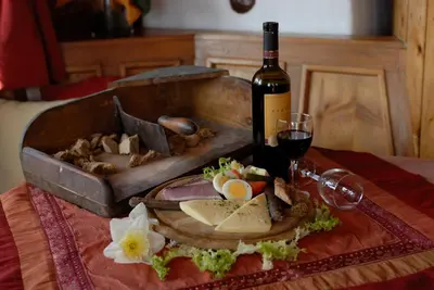 a table with a plate of food and a bottle of wine at Pension Schönblick in Campo di Trens