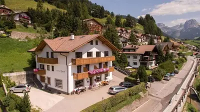a large white building on the side of a mountain at Hotel Garni Ruscel in Santa Cristina in Val Gardena