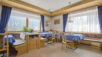 a dining room with blue tables and chairs and windows at Hotel Garni Ruscel in Santa Cristina in Val Gardena