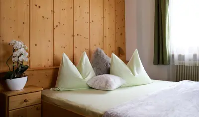 a bedroom with a bed with white pillows at Apartments Vaiolet in Santa Cristina in Val Gardena
