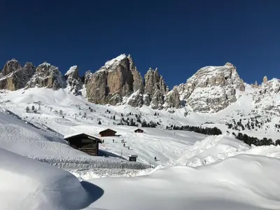 a snow covered mountain with a cabin in the foreground at Apartments Vaiolet in Santa Cristina in Val Gardena