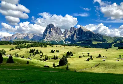 a green pasture with mountains in the background at Apartments Vaiolet in Santa Cristina in Val Gardena