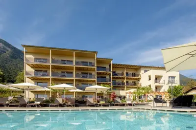 a hotel with a swimming pool with chairs and umbrellas at Brühl Suites&Residence in Caldaro