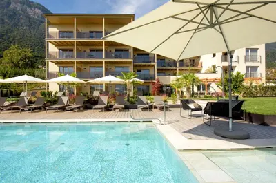 a hotel with a swimming pool with chairs and an umbrella at Brühl Suites&Residence in Caldaro