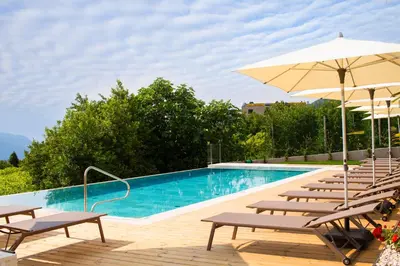 a swimming pool with chairs and an umbrella at Brühl Suites&Residence in Caldaro