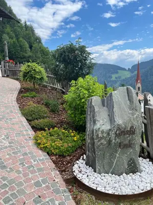 a rock in a garden next to a path at Apartment CANUS - Krumas Living - Kronplatz in San Lorenzo di Sebato