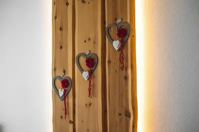 a wooden wall with three heart decorations on it at Apartment CANUS - Krumas Living - Kronplatz in San Lorenzo di Sebato