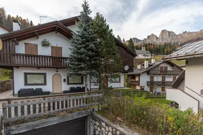 a home in the mountains with a wooden fence at Villa Eden in Falcade