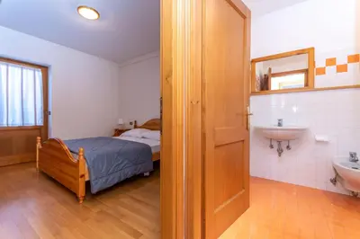 a bathroom with a bed and a sink in a room at Villa Eden in Falcade