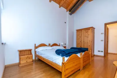 a bedroom with a bed and a wooden floor at Villa Eden in Falcade