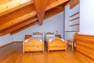 two beds in a room with wooden ceilings at Villa Eden in Falcade