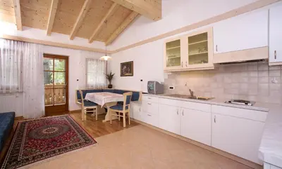 a kitchen with white cabinets and a table in a room at Garni-Hotel Pichler in Ortisei