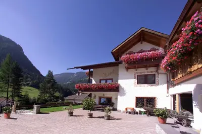 a kitchen with white cabinets and a table with chairs at Garni-Hotel Pichler in Ortisei