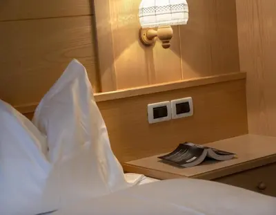 a bed in a bedroom with a wooden wall at Garni-Hotel Pichler in Ortisei