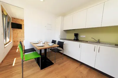 a kitchen with white cabinets and a table and chairs at Camping Zögghof in San Leonardo in Passiria