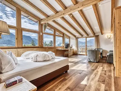 a bedroom with a bed in a room with windows at Hotel Traubenheim in Tirolo