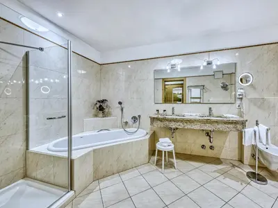 a bathroom with a tub and a sink and a shower at Hotel Traubenheim in Tirolo