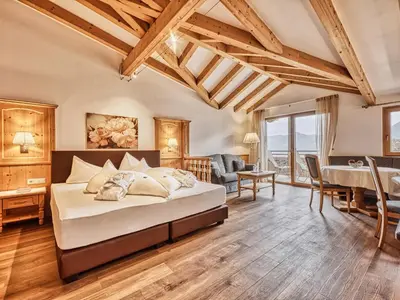 a bedroom with a large bed and a dining room at Hotel Traubenheim in Tirolo