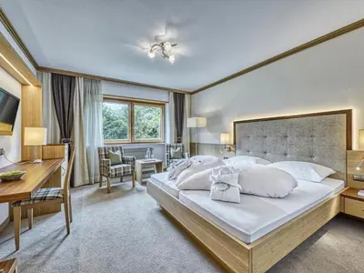 a bedroom with a large white bed and a desk at Hotel Traubenheim in Tirolo