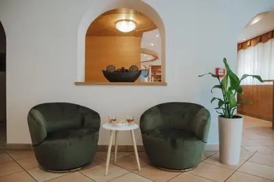 two green chairs and a table in a room at Hotel Elisabeth in Merano