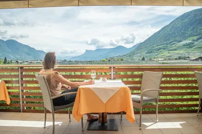 a woman sitting at a table with a glass of wine at Hotel Elisabeth in Merano