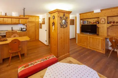 a living room with wooden cabinets and a kitchen at Casa Marmorata in Cortina dʼAmpezzo