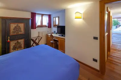 a bedroom with a blue bed and a desk at Casa Marmorata in Cortina dʼAmpezzo