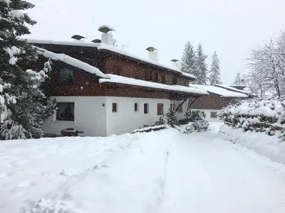 a house covered in snow in a yard at Casa Marmorata in Cortina dʼAmpezzo