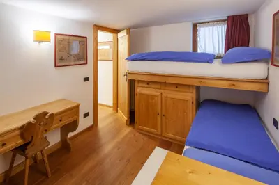 a bedroom with two bunk beds and a desk at Casa Marmorata in Cortina dʼAmpezzo