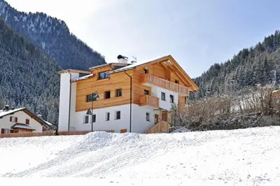 a house on a hill with snow in front of it at Apartments Cesa Leni in Bulla