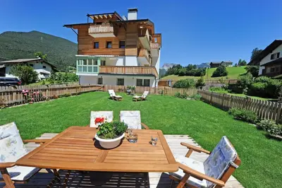 a wooden table and chairs on a yard with a house at Apartments Cesa Leni in Bulla