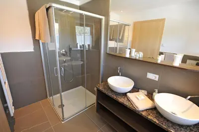 a bathroom with a glass shower and a sink at Apartments Cesa Leni in Bulla