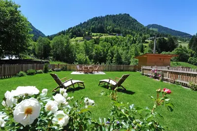 a yard with two chairs and a table and flowers at Apartments Cesa Leni in Bulla