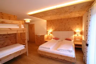 a room with two beds and a couch and a television at Lüch da Grones in San Vigilio Di Marebbe