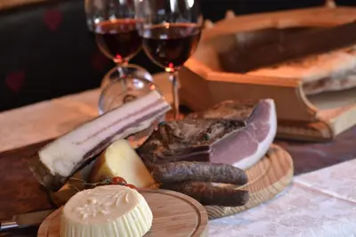 a plate of meats and cheese and glasses of wine at Lüch da Grones in San Vigilio Di Marebbe