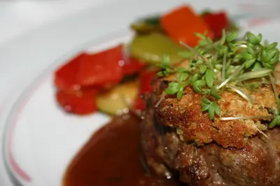 a plate of food with meat and sauce and vegetables at Lüch da Grones in San Vigilio Di Marebbe