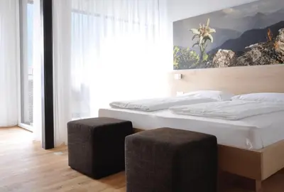 a bedroom with two beds and a large window at Alpenchalet Apartments in Parcines