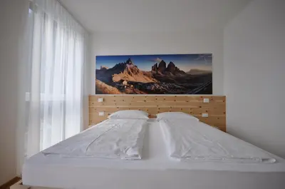 a bedroom with a bed with a picture on the wall at Alpenchalet Apartments in Parcines