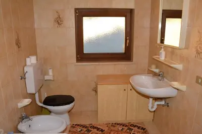 a bathroom with a toilet and a sink and a window at Appartamenti Vincenzo E Marcella in Campitello di Fassa