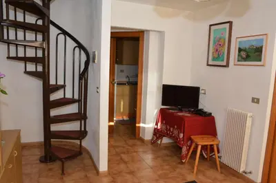 a room with a staircase and a desk with a television at Appartamenti Vincenzo E Marcella in Campitello di Fassa
