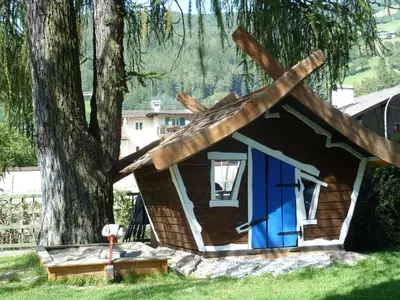 a log cabin with a blue door next to a tree at Appartements Margit in Vipiteno