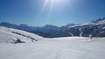 a snow covered mountain with the sun in the sky at Rododendro Apartment in Passo San Pellegrino