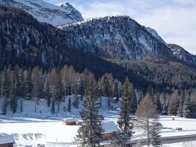 a snow covered mountain with a cabin in the foreground at Rododendro Apartment in Passo San Pellegrino