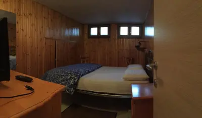 a bedroom with a bed in a room with wooden walls at Appartamento il Nido in Moena