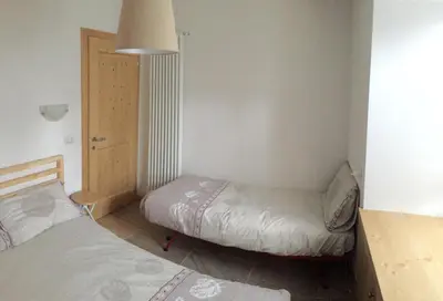 a small bedroom with two beds and a door at Appartamento il Nido in Moena
